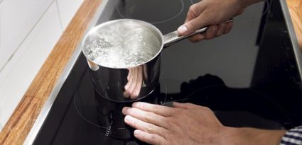 Imagem com pessoa fervendo água em fogão Cooktop