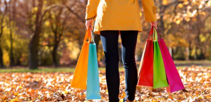 mulher com roupas de frio segurando sacolas de compras coloridas no Outono